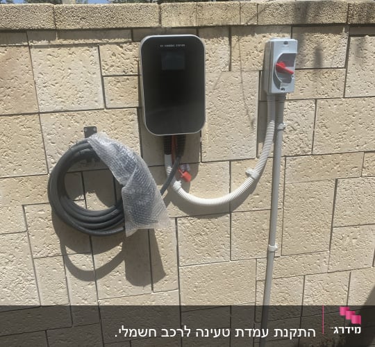 תחנת טעינה לרכב חשמלי על קיר אבן